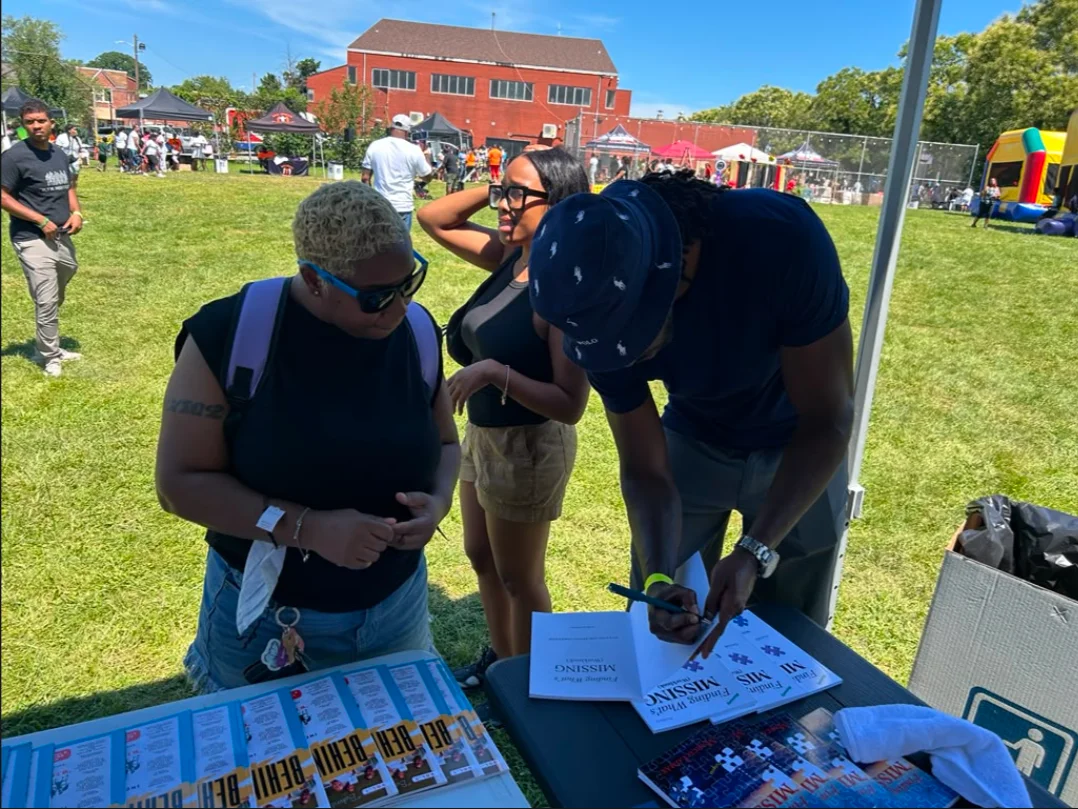 Marco Lomax signing copies of Finding What's Missing at an outdoor community event